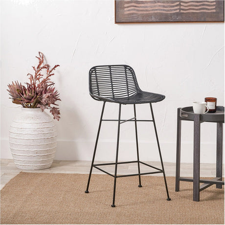 Black Rattan Core & Iron Bar Stool, 90cm, with woven seat and backrest on slim black metal legs with footrest, shown in a room beside a side table and vase.