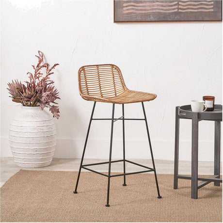 Rattan Core & Black Iron Bar Stool, 90cm, with woven natural rattan seat and black iron legs, shown in a room setting beside a plant and side table.
