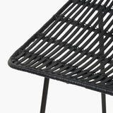 Close-up of the Black Rattan Core & Iron Dining Chair, showing woven black rattan strands over a metal frame with visible leg support, on a plain white background.