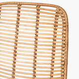 Close-up of the Rattan Core & Black Iron Dining Chair's backrest, showing woven natural rattan strands in a vertical open-slat pattern with a curved frame edge.
