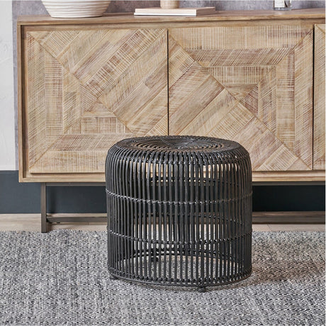 Black Rattan Core Stool, 44cm, with a round vertical-slat design, shown beside a light wood sideboard on a grey patterned rug.