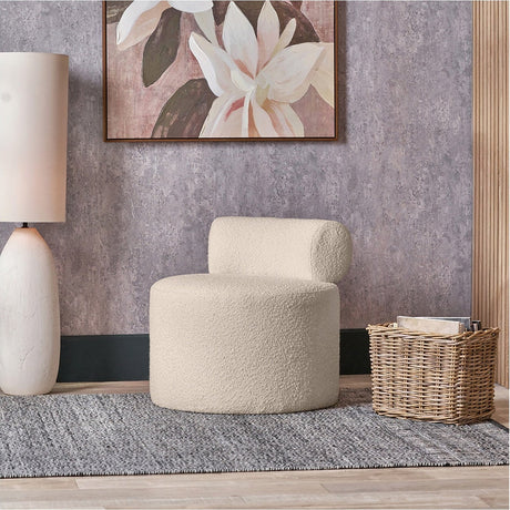 Assisi Taupe Teddy Fabric Modern Occasional Chair, 66cm wide, with rounded bolster backrest and cylindrical base, shown in a living room beside a woven basket and floral wall art.