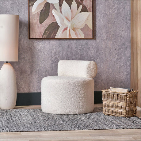Assisi White Boucle Fabric Modern Occasional Chair, 66cm, round bolster backrest, shown in a living room with a grey rug, floral wall art and a woven basket.