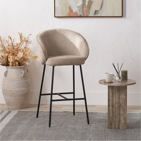 Kelsby tub bar stool with a curved mocha textured marl chenille back and low arms, set on slim black metal legs with a footrest, shown in a living room setting.