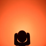 QTX 80W RGBWA COB LED moving head light by AVSL, silhouetted head and yoke shown front-on against a glowing orange backdrop.
