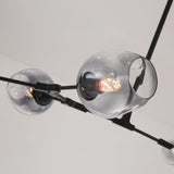 Close-up of the Tree 8 Light Suspension - Black, a modern chandelier with exposed LED bulbs inside clear glass globes on a sleek black frame, suspended from a plain white ceiling.
