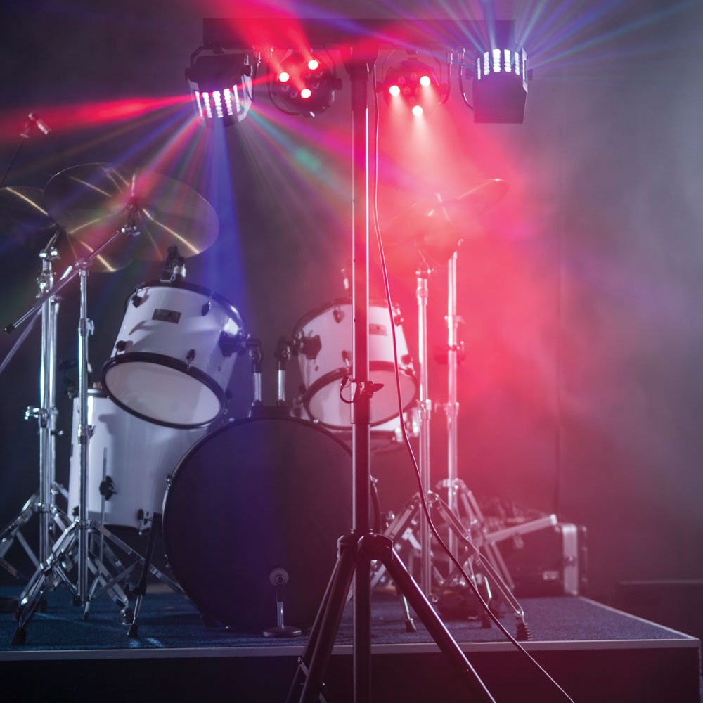 AVSL QTX LED Derby Par Can Light with tripod illuminating a drum kit on stage with red, blue and white RGBW beams through haze.