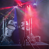 AVSL QTX LED Derby Par Can Light with tripod illuminating a drum kit on stage with red, blue and white RGBW beams through haze.