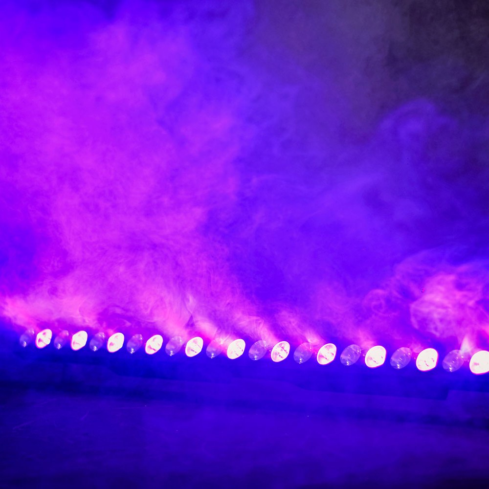 AVSL QTX 24x3W LED Wall Wash Bar lit in purple and amber, illuminating dense haze with a row of alternating RGB and amber beam emitters.