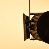 Side view of the Citronic MFZ100-W Mini Fresnel Zoom LED stage light with barn doors and mounting bracket, silhouetted against a warm amber background.
