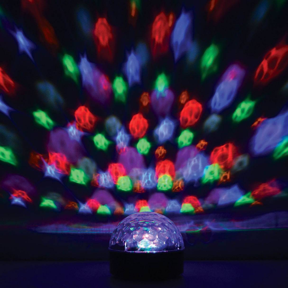 QTX Moonglow LED disco ball light effect projecting red, green, blue and purple beams across a dark wall from its clear faceted dome on a black base.