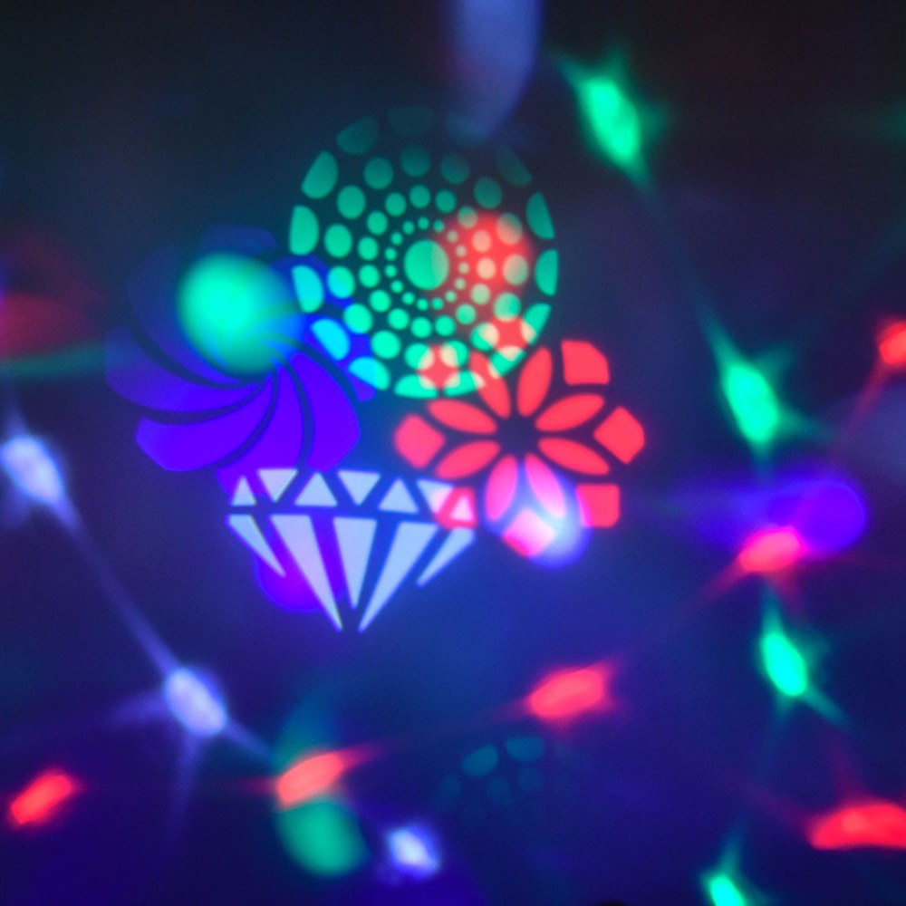 QTX Crystal Blaze RGBW tabletop LED light effect by AVSL projecting green, red, blue and white GOBO patterns of dots, flowers and a diamond across a dark room.