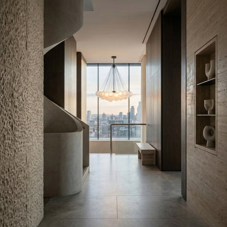 A modern hallway with textured stone walls, a sculptural staircase, minimalist built-in shelves, and a large window overlooking the city. The Orb 37 Light Cluster Suspension - Black chandelier hangs from the ceiling.