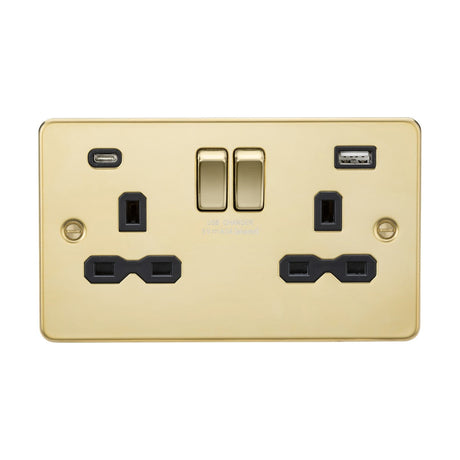 The 13A 2 Gang SP Switched Socket with Dual USB A+C, featuring a polished brass finish with a black insert and flat plate design, includes two UK-style three-pin outlets. It also has dual USB charging ports (A+C) and is distinguished by two centrally located switches against a plain white background.