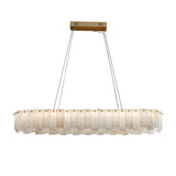 The Valeris 14 Light Layered Panel Alabaster Linear Chandelier in Soft White & Brass features oval-shaped, translucent alabaster panels suspended by four slim cables from a rectangular brass mount, creating a soft, glowing light effect.