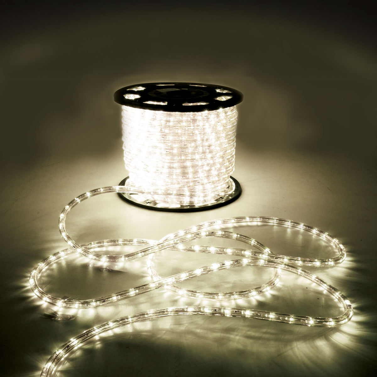 LYYT 50m LED rope light reel by AVSL, illuminated warm white 2800K, with clear flexible tubing coiled on the floor in a dim setting.