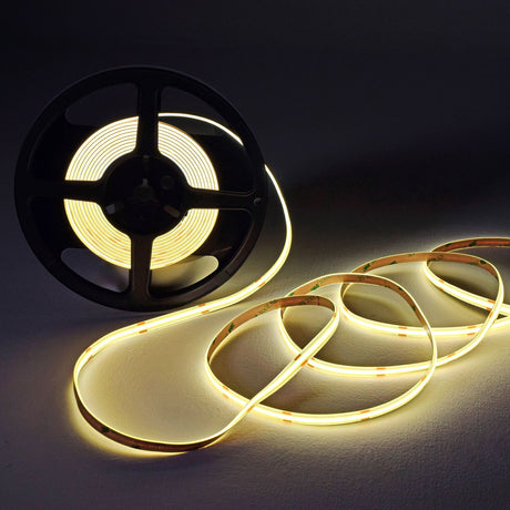 LYYT COBKITNW 24V COB LED tape kit with 5m reel partly unwound, emitting neutral white light in a continuous glow with 3M adhesive backing visible.