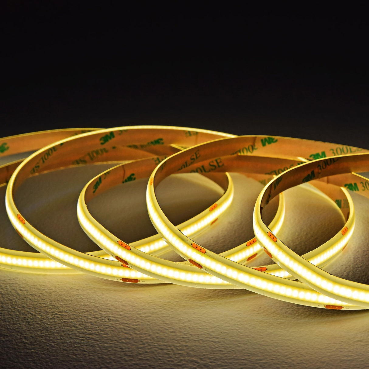 LYYT COBKITNW 24V COB LED tape coiled and illuminated in neutral white, showing dense LEDs on flexible strip with 3M 300LSE adhesive backing.