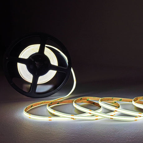 LYYT COBKITCW 24V COB LED tape kit shown partially unwound from a black reel, illuminated in cool white against a dark background.