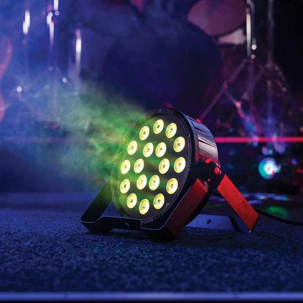 QTX 18x1.5W RGB LED Par Can by AVSL on a stage floor, black housing with 18 LEDs lit yellow-green, red bracket stand, amid haze and coloured lighting.