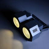 AVSL QTX 2x50W High Power LED Wash Light with two white COB LEDs in a compact matte black metal housing, side vents and mounting brackets visible.