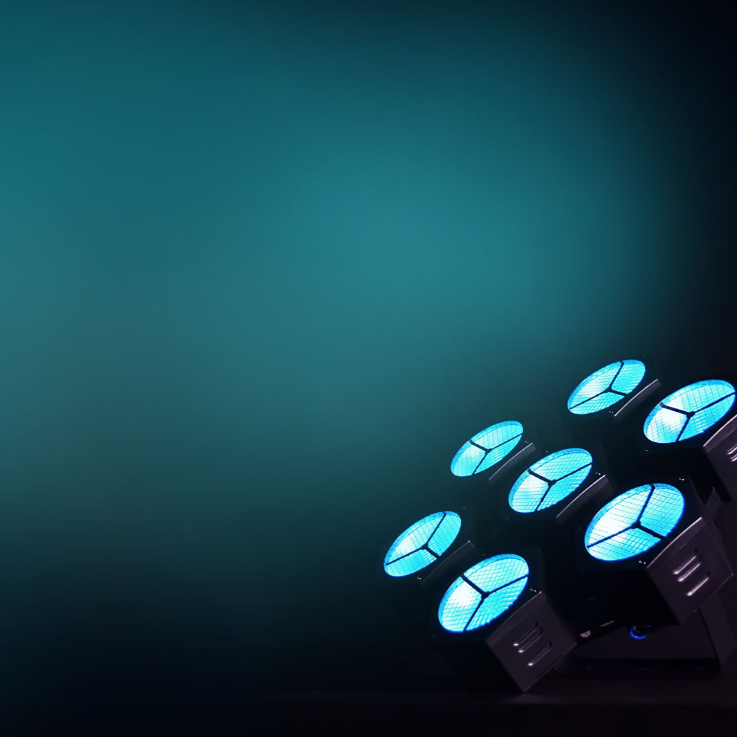 Citronic CosmoPAR PAR light by AVSL with seven glowing cyan RGBW COB LEDs in white housing, angled against a dark teal background.