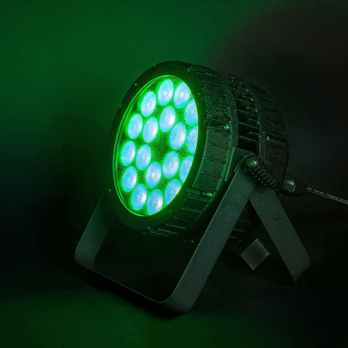 Citronic HIPAR-200 weatherproof LED PAR can on floor bracket, illuminated with green and cyan LEDs against a dark green misty background.