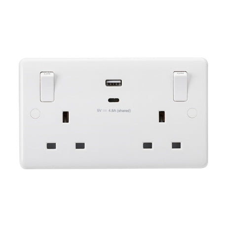 The 13A 2 Gang SP Switched Socket with Dual USB (5V DC 4.8A Shared) and Outboard Rockers offers a white electrical wall socket featuring two standard UK plug sockets, dual switches, and a central USB charger. The label under the USB port indicates a power rating of 5V 4.8A (shared), ensuring certified performance and enhanced safety standards.