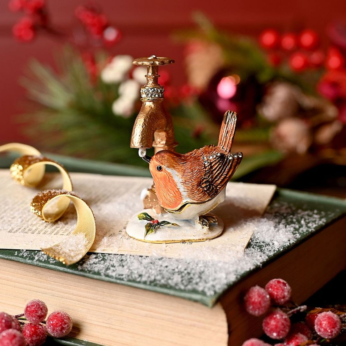 Robin Drinking from Tap hinged metal trinket box, hand-painted with orange breast and brown wings, gold tap, white snowy base, shown among festive holiday décor.