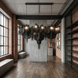 Niori Valora 15 Light Metal Chain Veil Chandelier in black, suspended by twin chains in an industrial loft with brick walls, concrete panels and wood floors.