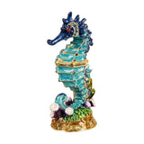 Hand-painted metal seahorse trinket box with hinged lid, turquoise and navy enamel, gold detailing, blue stone accents, and a coral and seaweed base.