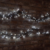 LYYT 960 LED outdoor string lights by AVSL, cool white LEDs clustered along a dark green cable draped across an exposed brick wall.