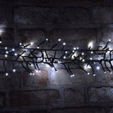 LYYT 960 LED outdoor string lights by AVSL illuminated in cool white along a dark green cable draped across a rustic exposed brick wall at night.