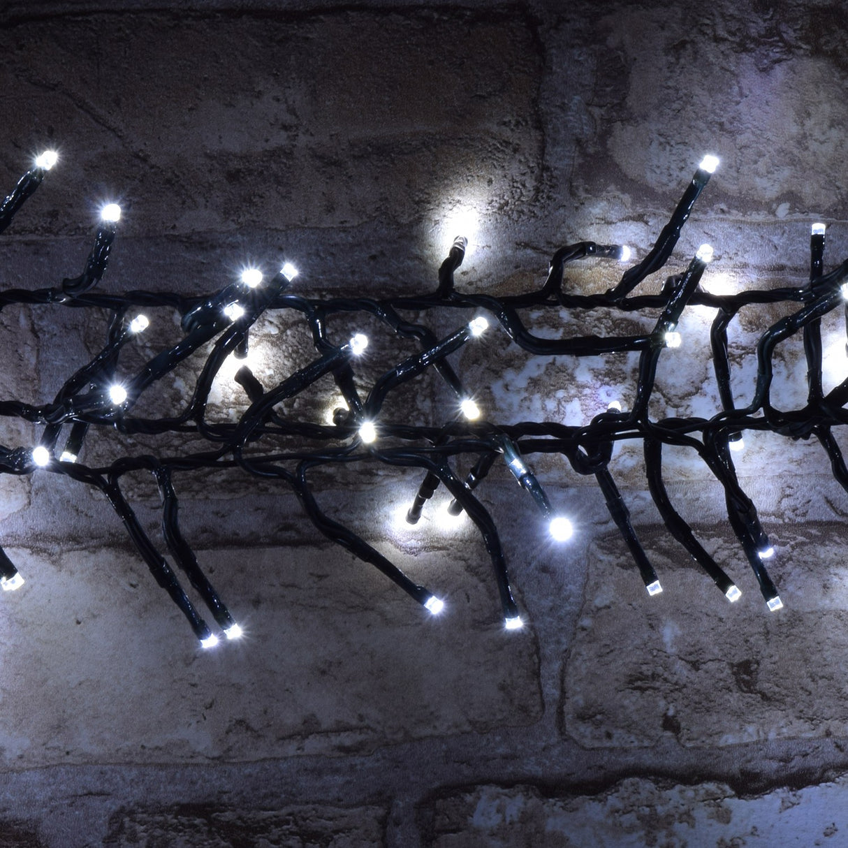 LYYT 960 LED outdoor string lights with cool white bulbs clustered along a dark green cable, draped against a rustic whitewashed brick wall.
