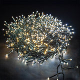 LYYT 960 LED outdoor string lights coiled in a dense cluster, glowing warm and cool white on dark green cable against a black background.
