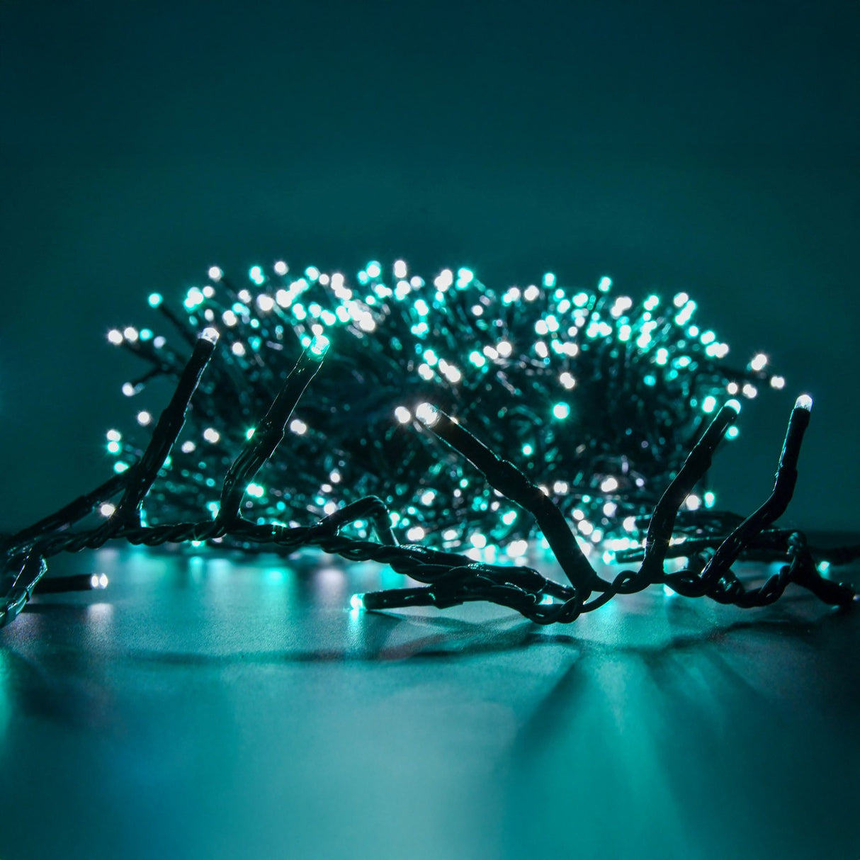 LYYT 960 LED cluster string lights by AVSL glowing cool white and blue, coiled with dark green cable against a teal background.
