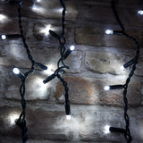 LYYT 180 LED outdoor icicle string lights in cool white with black rubber cable, shown lit against a rustic stone brick wall.