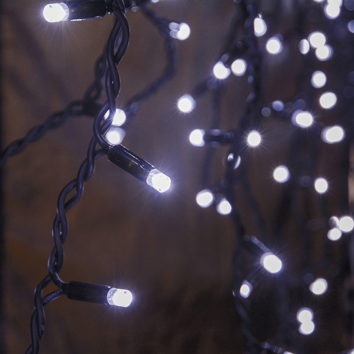 LYYT 180 LED outdoor icicle string light by AVSL shown lit at night with cool white LEDs cascading on black rubber cable in varying drop lengths.