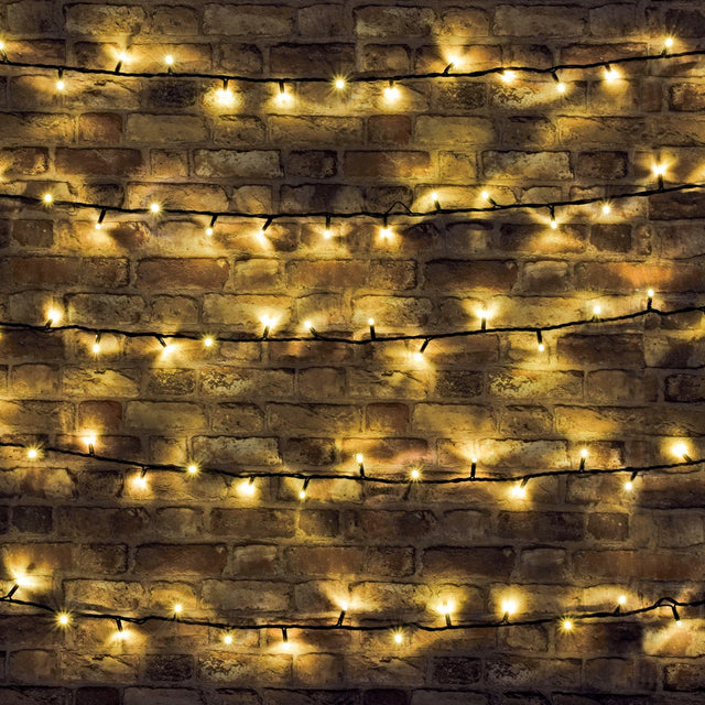 LYYT 180 LED heavy duty string lights in warm white draped in horizontal rows across a rustic exposed brick wall on black cable.