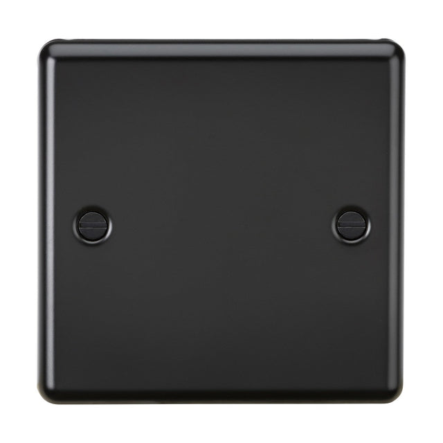 The 1 Gang Blanking Plate in matt black has a square shape and features a metal cover with two visible screw holes, one on each side. It boasts a smooth surface with rounded edges and complies with IEC 60670-1 standards.