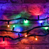 LYYT 90 LED heavy duty string lights in RGBA glowing red, green, blue and purple, draped in loops across a rustic exposed brick wall.