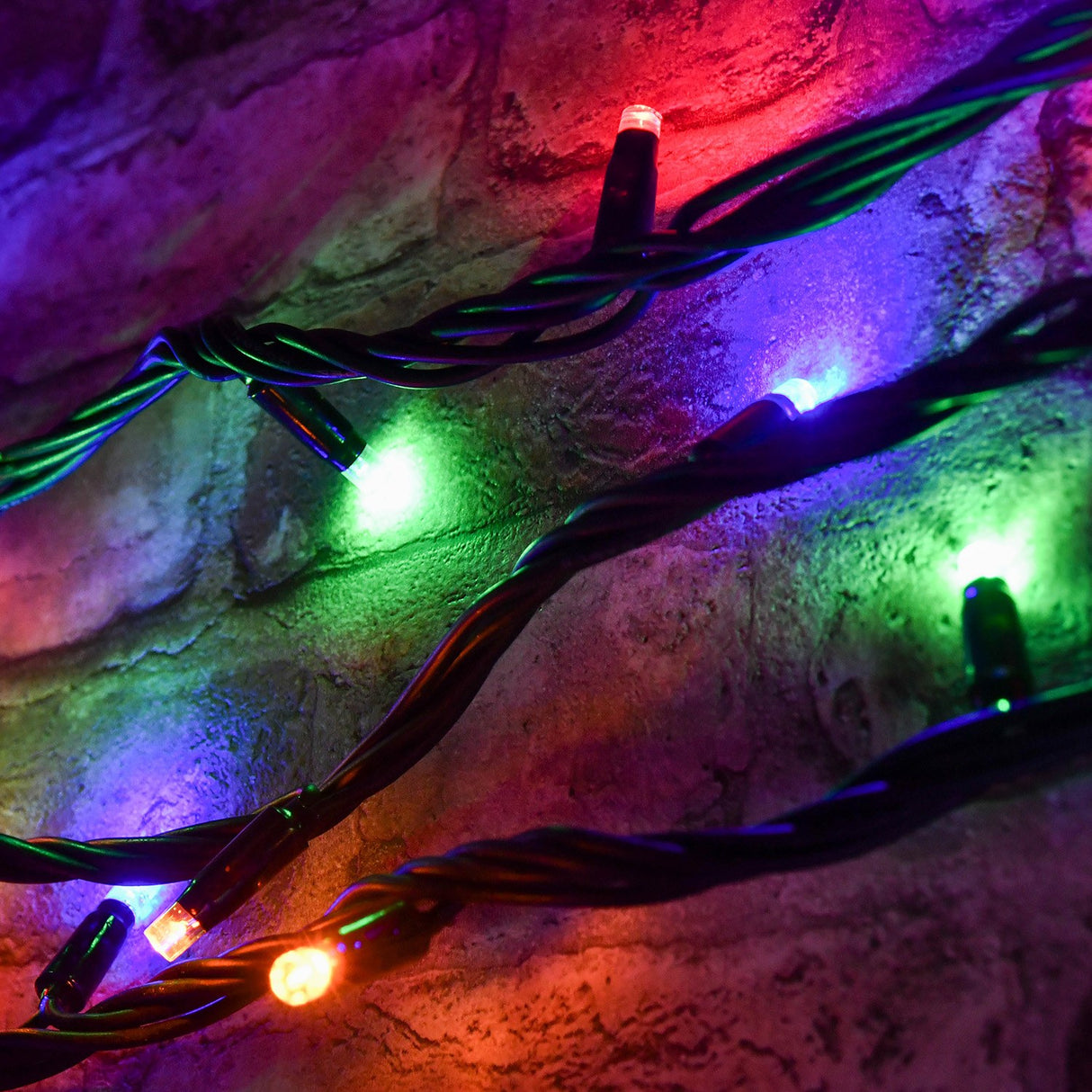 LYYT 90 LED heavy duty string lights in RGBA, shown lit in red, green, purple and amber against a stone wall with black rubber cable.