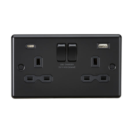 The "13A 2 Gang SP Switched Socket With Dual USB A+C - Matt Black (Black Insert, Rounded Edge)" is a sophisticated electrical wall socket with a decorative metal appearance. It includes two standard power outlets, a USB-C port, and a USB-A port labeled "USB Charger 5V ⎓ 4.0A (shared)." This sleek charger socket also features two switches for enhanced functionality.