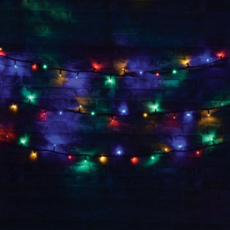 LYYT's 180 LED Heavy Duty Static String Lights, at a length of 20 meters, are draped across a dark brick wall, producing a festive and vibrant display with RGBA (red, green, blue, and amber) bulbs illuminating the dim background. These energy-efficient lights are ideal for outdoor use.