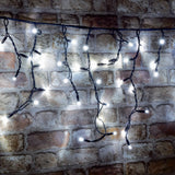 LYYT cool white LED icicle string lights with cascading drops on black cable, illuminated against an exposed brick wall.