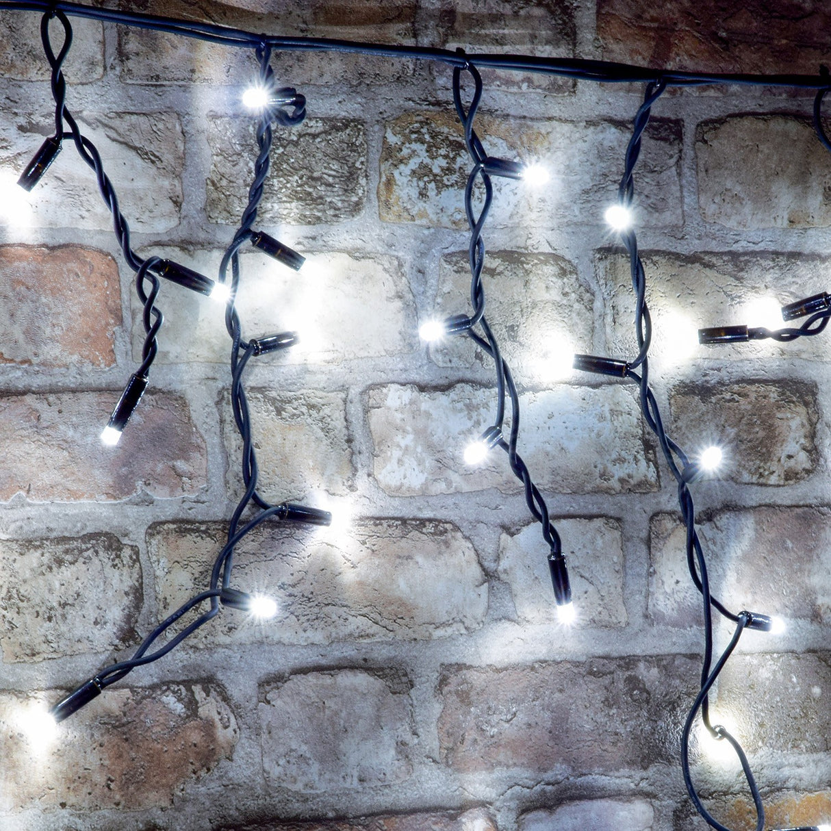 LYYT 100CONI-CW cool white connectable icicle lights illuminated in cascading drops with black cable against an exposed brick wall.