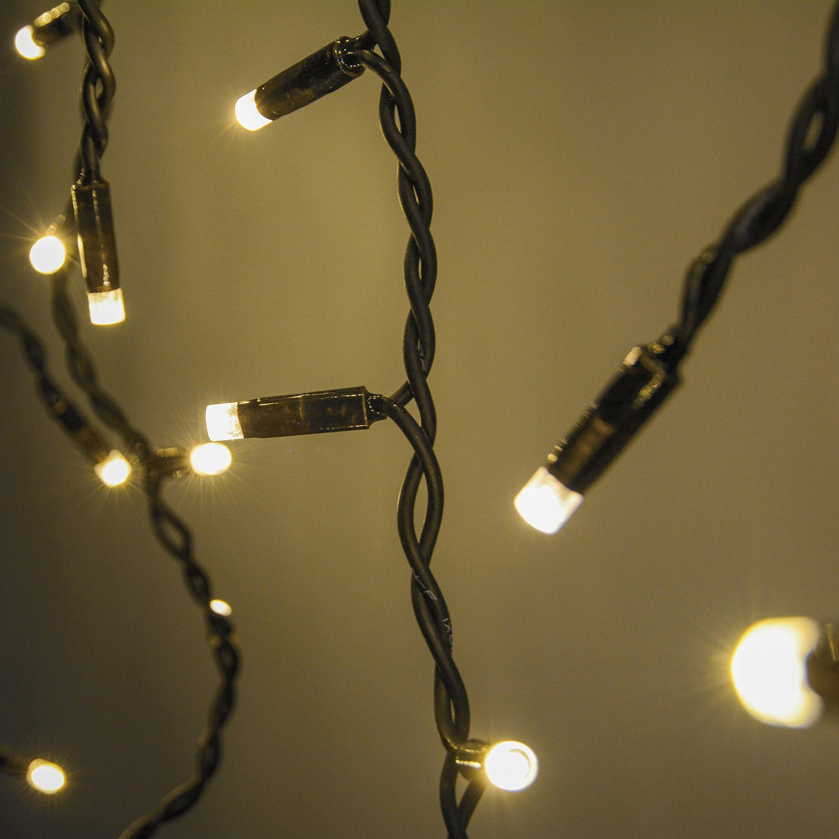 Close-up of LYYT 100CONI-WW warm white icicle string lights with lit LEDs on twisted black cable at varying drop lengths.