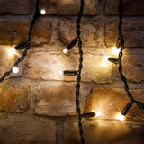 LYYT 100CONI-WW warm white icicle string lights with LED bulbs on black cable, draped against a rustic brick wall.