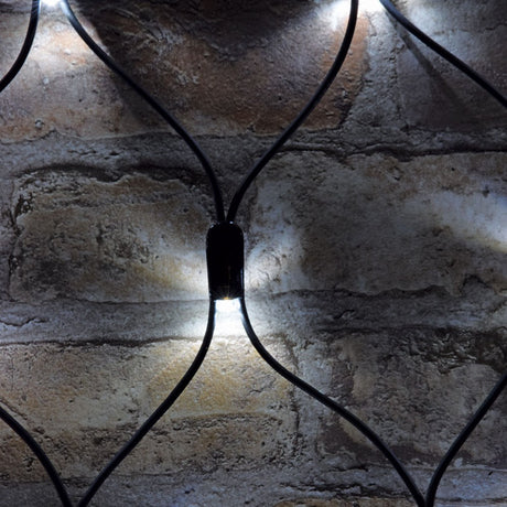 Close-up of AVSL LYYT 144NET-CW Cool White Connectable Net Light showing black rubber mesh cable and one lit concave LED head against a brick wall.