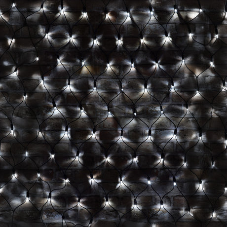 A close-up view of a brick wall with black wire netting features the LYYT 144 LED Outdoor Connectable Net Light, 1.2m in cool white. These energy-efficient LEDs are woven into the netting, creating a shimmering pattern across the dark surface.